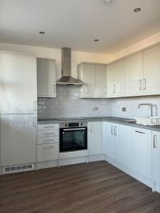 uma cozinha com armários brancos e um forno com placa de fogão em Spacious 2BR with balcony in Brentwood em Brentwood