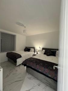 2 bedden in een slaapkamer met witte muren en marmeren vloeren bij Luxury Travis House in Burnley