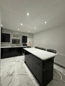 a large kitchen with a white counter and chairs at Luxury Travis House in Burnley