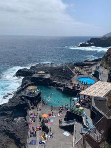 un grupo de personas en una playa cerca del océano en Balcón del Puerto, Ático-Solarium, en Tazacorte