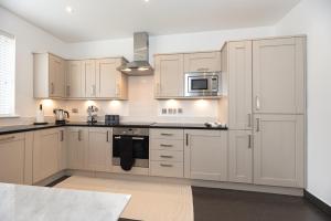 a kitchen with white cabinets and stainless steel appliances at 3-Bedroom Flat with FREE parking in the Heart of Hampton Hill Village in Hampton Hill