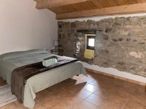 1 dormitorio con cama y pared de piedra en Angrill en Lladurs