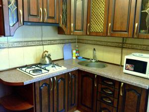 a kitchen with a stove and a sink and a microwave at Petropavlovskaya in Sumy
