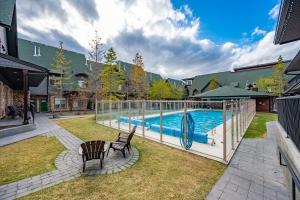 a swimming pool in a yard with two chairs at Grotto Canyon Chalet in Canmore