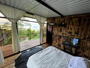 1 dormitorio con 1 cama y balcón con ventana en Cabaña Aurora de Silvania, en Silvania