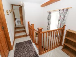 pasillo con escalera de madera y ventana en Corran Cottage, en Carmarthen