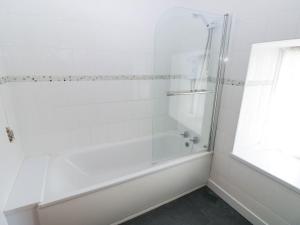 Un baño blanco con bañera y ducha. en Corran Cottage, en Carmarthen 24 fotos más