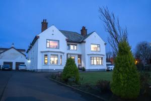 a large white house with its lights on at Larkhill House in Portrush