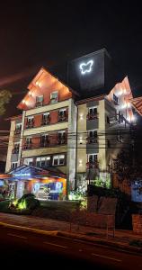 un bâtiment avec un panneau en haut de celui-ci la nuit dans l'établissement Hotel Querência, à Gramado