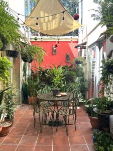 un patio con mesa, sillas y una pared roja en Hotel Andoria, en San Salvador