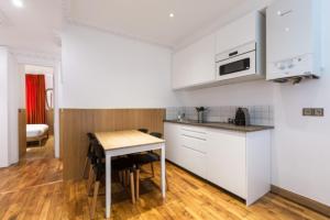une cuisine avec des placards blancs et une petite table dans l'établissement Escapade Familiale à Grenelle, à Paris