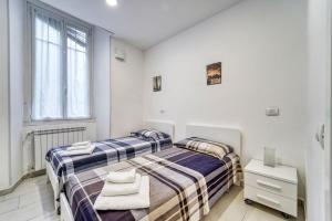 two beds in a room with white walls at Residenza via carloni 18 in Como