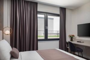 a hotel room with a bed and a desk and a window at HADRIE LUXURY RESORT AND VILLAS ROVA b in Vantačići +35 photos