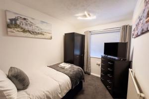 a bedroom with a bed and a dresser with a television at Immaculate 5 Bedroom House in Rockingham