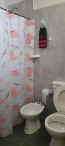 a bathroom with a toilet and a shower curtain with a sink at Departamentos “Don Ramon” in Villa Cura Brochero