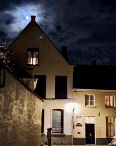 Una gran casa blanca con una luna en el cielo en Hamiltonhouse en Brujas