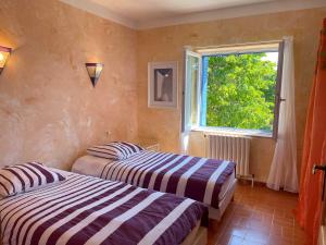 2 Betten in einem Zimmer mit Fenster in der Unterkunft Mas des Lavandes - 3 gîtes de charme au calme avec grande piscine en Drôme-Provençale in Suze-la-Rousse