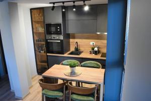 a kitchen with a wooden table with chairs and a sink at The Royal Pine Apartment Mavrovo in Mavrovo