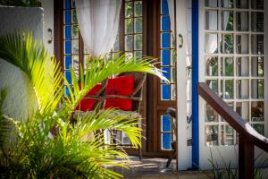 a porch with a red chair and a door at Pousada Lestada by Latitud Hoteles in Búzios