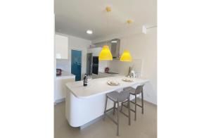 una cocina con una isla blanca con taburetes en Luxury apartment in Higuerón - Serenity en Málaga