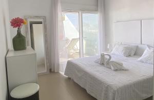 Un dormitorio blanco con una cama y un jarrón con flores. en Luxury apartment in Higuerón - Serenity en Málaga