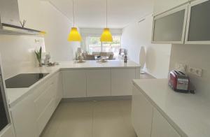 una cocina blanca con armarios blancos y fregadero en Luxury apartment in Higuerón - Serenity en Málaga