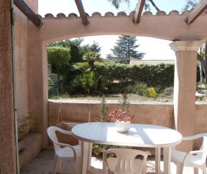 una mesa blanca y sillas en un patio con un arco en Rez de Villa Climatisé avec Jardin Privatif Domaine des Moulières en La Valette-du-Var