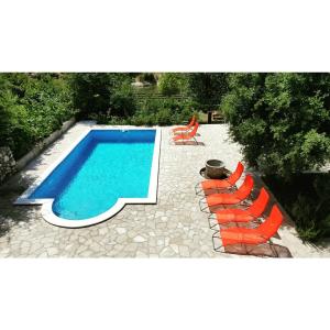 a swimming pool with orange chairs and a swimming pool at Villa Velagic in Blagaj