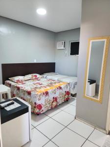 a small room with two beds and a mirror at Condomínio Center luz in Teresina