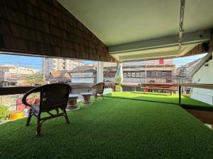 a room with chairs and a green floor with a large window at One More Space in Chiang Mai