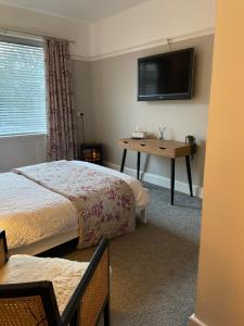 a bedroom with two beds and a desk and a television at Larkhill House in Portrush