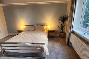 a bedroom with a bed with two lamps and a window at Spacious Guest Flat near Roundhay Park in Roundhay