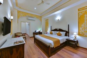 a hotel room with a bed and a television at WelcomHeritage Ramgarh in Panchkula