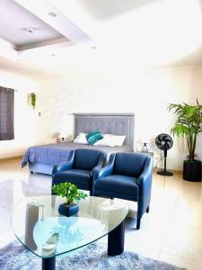 1 dormitorio con 1 cama, 2 sillas azules y una mesa en Casa boka con vista al mar y alberca, en Boca del Río