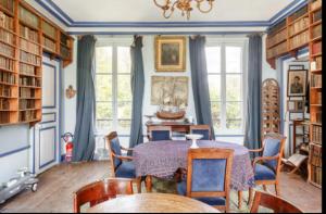 ein Esszimmer mit einem Tisch, Stühlen und Fenstern in der Unterkunft Domaine du Parc et Château de Manou in Manou