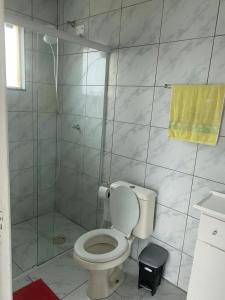 a bathroom with a toilet and a shower with a yellow towel at Pousada dos Reis in Barra de Ibiraquera