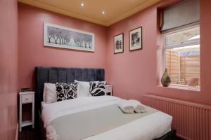 sypialnia z różowymi ścianami i dużym łóżkiem w obiekcie Stylish 2 Bedroom Flat, Sleep 6 & Garden London Zone 2 cls Central w Londynie