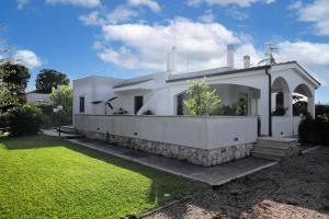 a white house with a stone wall and a yard at Dimora Pacelli in Castellana Grotte