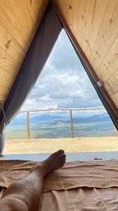 ein auf einem Bett liegendes Bein mit Blick aus dem Fenster in der Unterkunft A Chave da Montanha 