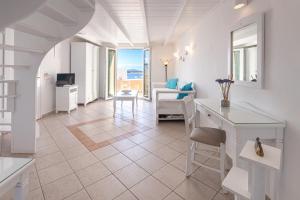 a white living room with a table and chairs at Reverie Santorini Hotel in Firostefani