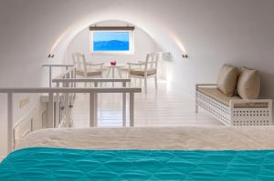 a bedroom with a bed and a table and chairs at Reverie Santorini Hotel in Firostefani