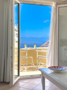 balcón con mesa y vistas al océano en Reverie Santorini Hotel, en Firostefani