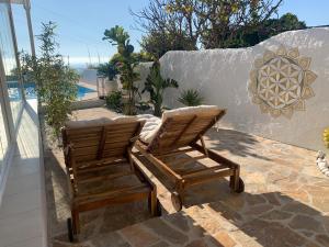 dwa drewniane krzesła siedzące na patio przy ścianie w obiekcie Villa Pura Vida w mieście Nerja