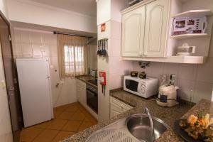 a kitchen with white cabinets and a sink and a microwave at Ericeira Beach by AcasaDasCasas in Ericeira