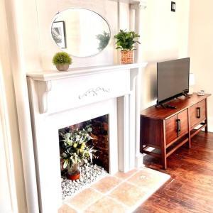 ein Wohnzimmer mit einem Kamin, einem Spiegel und einem TV in der Unterkunft Historic Cottage in Five Points near Downtown in Huntsville