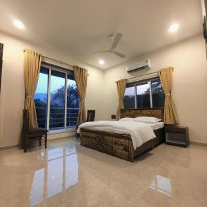 een slaapkamer met een bed en een groot raam bij Kasturi Villa - A home away from home in Mandve