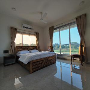 um quarto com uma cama grande e janelas grandes em Kasturi Villa - A home away from home em Mandve