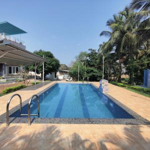 uma piscina num resort com palmeiras em Kasturi Villa - A home away from home em Mandve