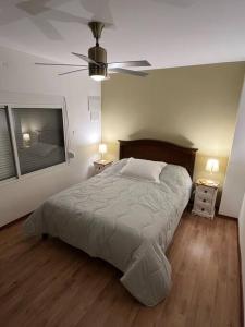 a bedroom with a bed and two tables and a fan at Casa moderna y recién terminada in Maldonado