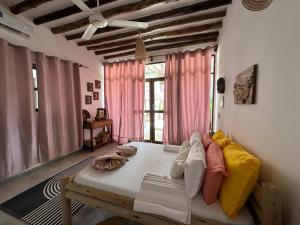 a room with a bed and a window with pink curtains at Olamanga Beach Villa in Jambiani